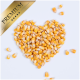 Herzförmige Anordnung von gelben Maiskörnern auf einem weißen Hintergrund, mit einem goldenen Etikett "PREMIUM" in der oberen Ecke.