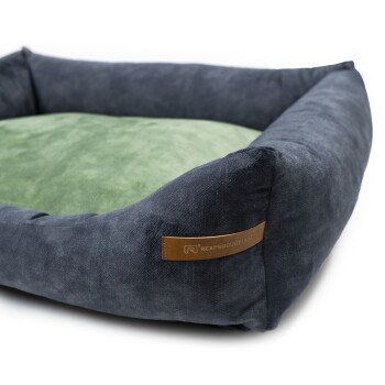Ein gemütliches Haustierbett mit einem dunkelblauen Äußeren und einem weichen grünen Inneren, mit einem kleinen Lederetikett, das "RexProduct.com" liest.