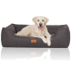 Ein Golden Retriever liegt bequem auf einem dunkelgrauen Haustierbett mit einem Lederschild mit der Aufschrift "Kruuse." Das Bett hat ein modernes Design.