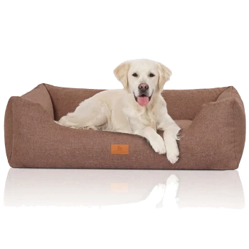 Ein flauschiger weißer Hund entspannt sich auf einem gemütlichen braunen Haustierbett mit einem Lederetikett, das Komfort und Stil zeigt.