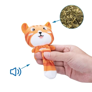 Eine Person hält ein orangefarbenes Plüschkatzen-Spielzeug mit einem lächelnden Gesicht und einem Schallsymbol, neben einem kreisförmigen Ausschnitt von getrockneten Kräutern.