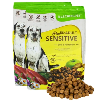 Zwei Beutel "Paula's Adult Sensitive" Hundefutter (Ente und Kartoffeln) mit verstreutem Futter, das die Eignung für Allergien betont.