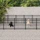 Zwei Hunde, ein schwarzer Labrador und ein gelber Labrador, stehen in separaten schwarzen Metallgehegen auf einem gepflasterten Boden, umgeben von Grün.