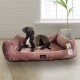 Ein schwarz-weißer Hund, der auf einem plüschigen rosa Hundebett entspannt, mit einem sichtbaren Etikett, das die Marke "tierlando" zeigt.