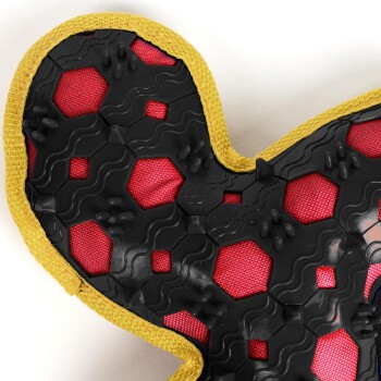 Close-up of a red and black rubber dog chew toy with yellow fabric trim, featuring textured hexagonal patterns.