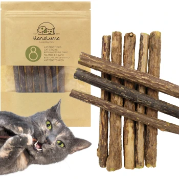 Eine verspielte graue Katze, die an einem Katzenstick kaut, mit einer Verpackung, die "Karaluna Cat Sticks" enthält, mit 8 Sticks im Hintergrund.