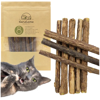 Eine verspielte graue Katze, die an einem Katzenstick kaut, mit einer Verpackung, die "Karaluna Cat Sticks" enthält, mit 8 Sticks im Hintergrund.