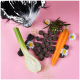 Ein schwarz-weißer Hund schnüffelt an verschütteten dunkelbraunen Haustierleckerlis aus einem grünen und rosa Behälter mit der Aufschrift "Dampfle Drops" auf einem rosa Hintergrund.