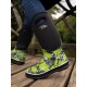 Eine Nahaufnahme der Beine einer Person, die stilvolle schwarze und grüne gemusterte wasserdichte Stiefel mit dem Logo "Two Tracks" trägt, auf einer Holzoberfläche stehend.