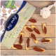 Eine Tüte Lyra-Hundeleckerlis ist teilweise geöffnet und zeigt mehrere fischförmige Snacks mit einer rötlich-braunen Füllung, die auf einer Holzoberfläche verstreut sind.