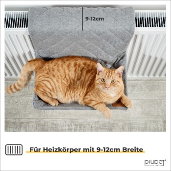 Eine entspannte orange getigerte Katze, die auf einem grauen Haustierbett liegt, das in der Nähe eines Heizkörpers positioniert ist, mit einem Etikett, das 'Für Heizkörper mit 9-12cm Breite' angibt.