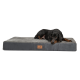 Ein schwarz-brauner Dobermann liegt bequem auf einem grauen Haustierbett mit einem Lederschild mit der Aufschrift 'terranova'.