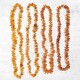 Vier Stränge von bernsteinfarbenen Haustierhalsketten aus polierten Steinen, auf einem hellen Holzuntergrund präsentiert.