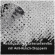 Nahaufnahme eines strukturierten schwarzen Stoffes mit Anti-Rutsch-Punkten, beschriftet "Atmungsaktives Unterseitenvlies mit Anti-Rutsch-Stoppern."