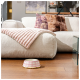 Pink-weiß kariertes Haustierfutternapf auf Holzboden vor einem beigen Sofa mit rosa Decke und dekorativen Kissen.