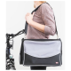 Eine Frau in einem leichten Pullover hält eine schwarze und graue Haustiertragetasche mit Schultergurt und steht neben einem Fahrrad.