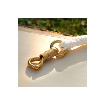 Nahaufnahme eines goldenen Metallclips, der an einem weißen geflochtenen Seil befestigt ist, auf einer hellen Holzoberfläche mit grünem Gras im Hintergrund.