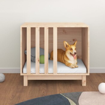Ein glücklicher Corgi, der auf einem weißen Kissen in einer hölzernen Haustierkiste ruht, mit einem grauen Kissen und einem grünen Ball neben sich.