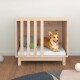 Ein glücklicher Corgi, der auf einem weißen Kissen in einer hölzernen Haustierkiste ruht, mit einem grauen Kissen und einem grünen Ball neben sich.