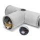 Eine verspielte getigerte Katze schaut aus einem weichen, grauen Katzentunnel mit zwei Öffnungen und einem baumelnden Pom-Pom-Spielzeug heraus.