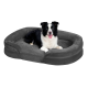 Schwarz-weißer Border Collie liegt auf großem grauem Plüsch-Hundebett mit erhöhten Seiten vor weißem Hintergrund.