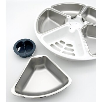 Eine Futterstation für Haustiere mit einer weißen Basis und vier Edelstahlschüsseln sowie einer dunkelblauen abnehmbaren Schüssel mit zwei Fächern.