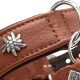 Nahaufnahme eines braunen Lederhundehalsbands mit silberner Blumen-Niete, Metall-D-Ringen und Anhänger mit teilweise sichtbarem Text 'HU'.