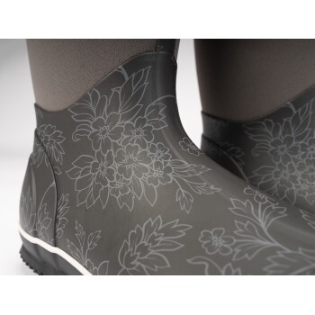 Nahaufnahme von stilvollen grauen Gummistiefeln mit floralen Mustern, mit einer strukturierten Oberseite und einer weißen Sohle.