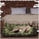 Ein entspannter grauer Hund, der in einem camouflagemusterierten Haustierbett liegt, mit einer gemütlichen Strickdecke und Kissen im Hintergrund.