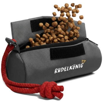 Ein grauer Haustierfutterbeutel mit einem roten Kordelzug, beschriftet mit "RUDELKÖNIG," der Futter auf einen weißen Hintergrund auskippt.