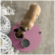 Ein tanfarbener Hund mit einem schwarzen Halsband frisst aus einer weißen Schüssel, die mit Trockenfutter gefüllt ist, auf einer rosa Fütterungsmatte, mit einer grauen Wasserschüssel in der Nähe.