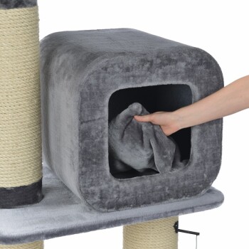 Eine Hand zieht eine weiche graue Decke aus einer gemütlichen, grauen Haustierhöhle auf einem Katzenbaum, der einen Kratzbaum hat.