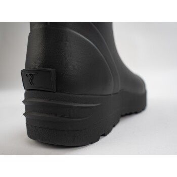 Nahaufnahme der Ferse eines schwarzen Gummistiefels, mit einer strukturierten Oberfläche und einem kleinen Logo auf der Rückseite.