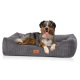 Ein glücklicher Australian Shepherd Hund liegt auf einem plüschigen grauen Haustierbett mit Cord-Textur, mit einem Lederetikett, das "KNUFFELWUFF" liest.