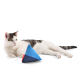 Eine entspannte weiße Katze mit schwarzen Flecken liegt neben einem bunten dreieckigen Spielzeug, das blaue, rote und dunkelblaue Abschnitte aufweist.