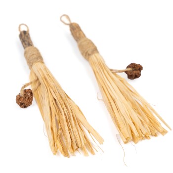 Zwei natürliche Haustierkauspielzeuge aus getrocknetem Gras, mit Schnur gebunden, mit kleinen braunen Kugeln an den Enden.
