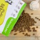 Eine Tüte Haustierfutter mit der Aufschrift "Paula's" von Lecker.Pet, mit braunen Kroketten, die auf einer Holzoberfläche verschüttet sind, und einem Seilspielzeug in der Nähe.
