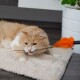 Eine flauschige orange-weiße Katze, die verspielt an einem Feder-Spielzeug kaut, während sie auf einem weichen, beigen Teppich liegt.