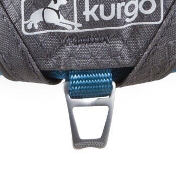 Nahaufnahme eines grauen Kurgo-Hundegeschirrs mit einem blauen Riemen und einem metallenen D-Ring zur Leinenbefestigung.