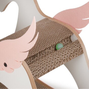 Ein skurriler Kratzbaum für Katzen in Form eines Pferdes, mit rosa Flügeln und einer strukturierten Pappoberfläche, mit einem grünen Ball darunter versteckt.