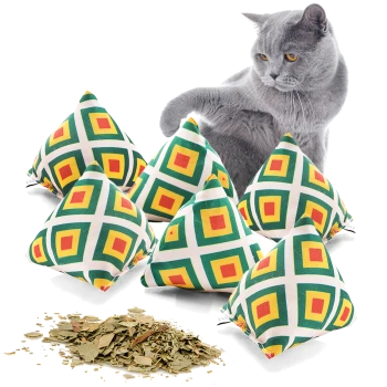 Eine graue Katze spielt mit sechs bunten pyramidenförmigen Katzenminze-Spielzeugen, mit getrockneter Katzenminze, die davor verstreut ist.