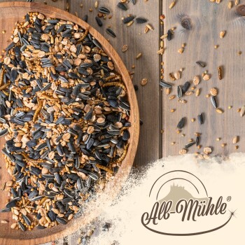 Eine Holzschale mit gemischtem Vogelfutter, einschließlich Sonnenblumenkerne, auf einer Holzoberfläche mit dem "All-Mühle"-Logo in der Ecke.