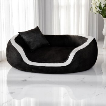 Schwarz-weißes Plüsch-Haustierbett mit passendem Kissen, auf glänzendem Marmorboden neben weißen Vorhängen platziert.