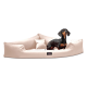 Ein schwarz-brauner Dackel sitzt auf einem plüschigen, beigen Hundebett mit erhöhten Rändern und einem kleinen Kissen, das Komfort und Stil zeigt.