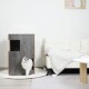 Eine flauschige weiße Katze taucht aus einem modernen, dunkelbraunen Katzenhaus mit einem Ausschnitt-Eingang auf, das in einem stilvollen Wohnzimmer mit einem cremefarbenen Sofa und einem hellen Teppich steht.