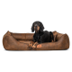 Ein schwarzer Hund, der bequem auf einem braunen Haustierbett mit strukturierter Oberfläche ruht, mit einem kleinen Lederetikett, das "terrandar" beschriftet ist.