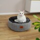 Eine weiße Katze mit gelb-grünen Augen sitzt bequem in einem runden, grauen Haustierbett mit schwarzem Innenraum, das ein kleines Lederetikett hat.