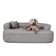 Ein graues Hundebett mit einem plüschigen Design, auf dem ein Hund bequem liegt, begleitet von einem kleinen Kissen.