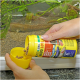 Une personne verse de la nourriture pour poissons d'un conteneur jaune JBL étiqueté 'PRO JBL NOVO LOTL' dans un petit bouchon, avec un aquarium en arrière-plan.