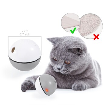 Eine graue Katze, die neugierig mit einem kleinen, runden interaktiven Spielzeugball interagiert, der 7 cm (2,7 Zoll) misst und ein rotes Licht hat.